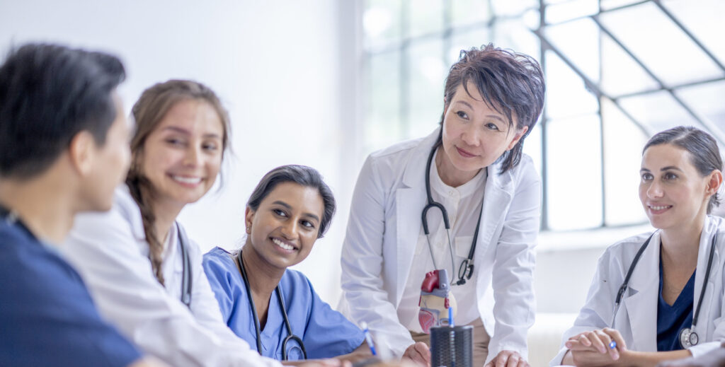 Medical professionals in lab coats, wearing stethoscopes, sitting around a table.